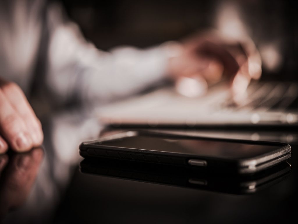 A phone on a desk while a professional works in the background